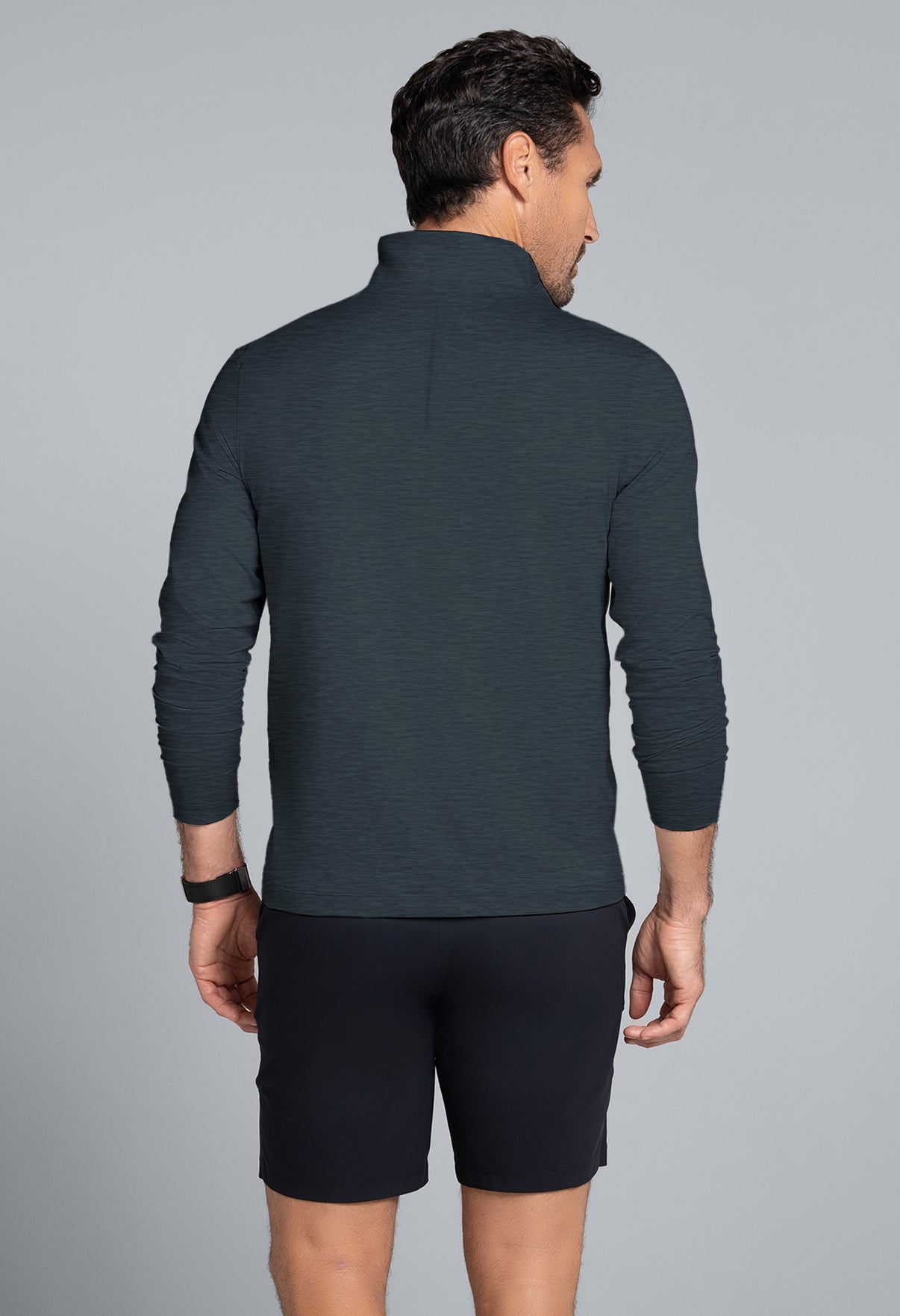 Man wearing a dark gray long-sleeve shirt and black shorts on a gray background