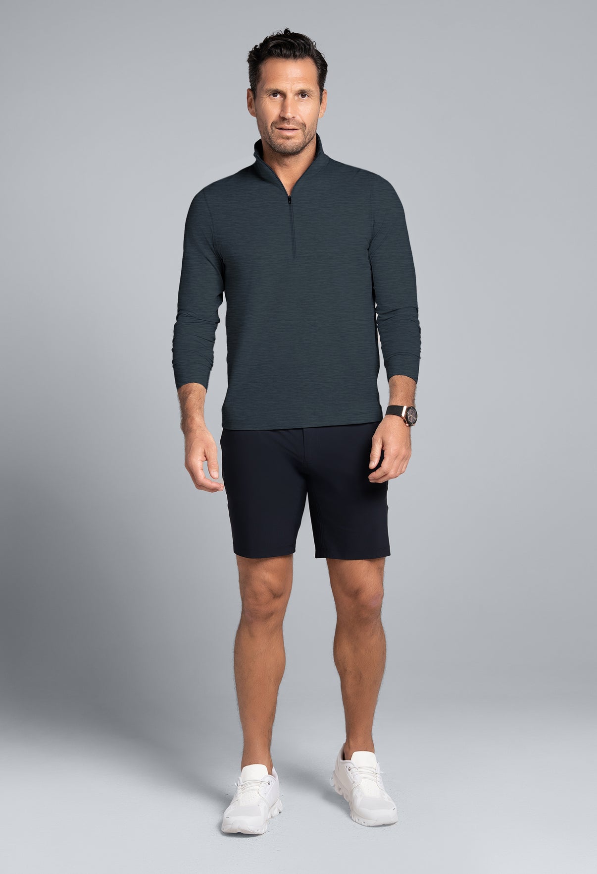 Man wearing a dark gray long-sleeve shirt and black shorts on a gray background