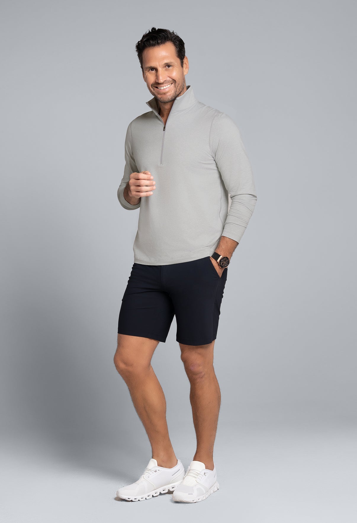 Man wearing a gray zip-up sweater and black shorts on a gray background