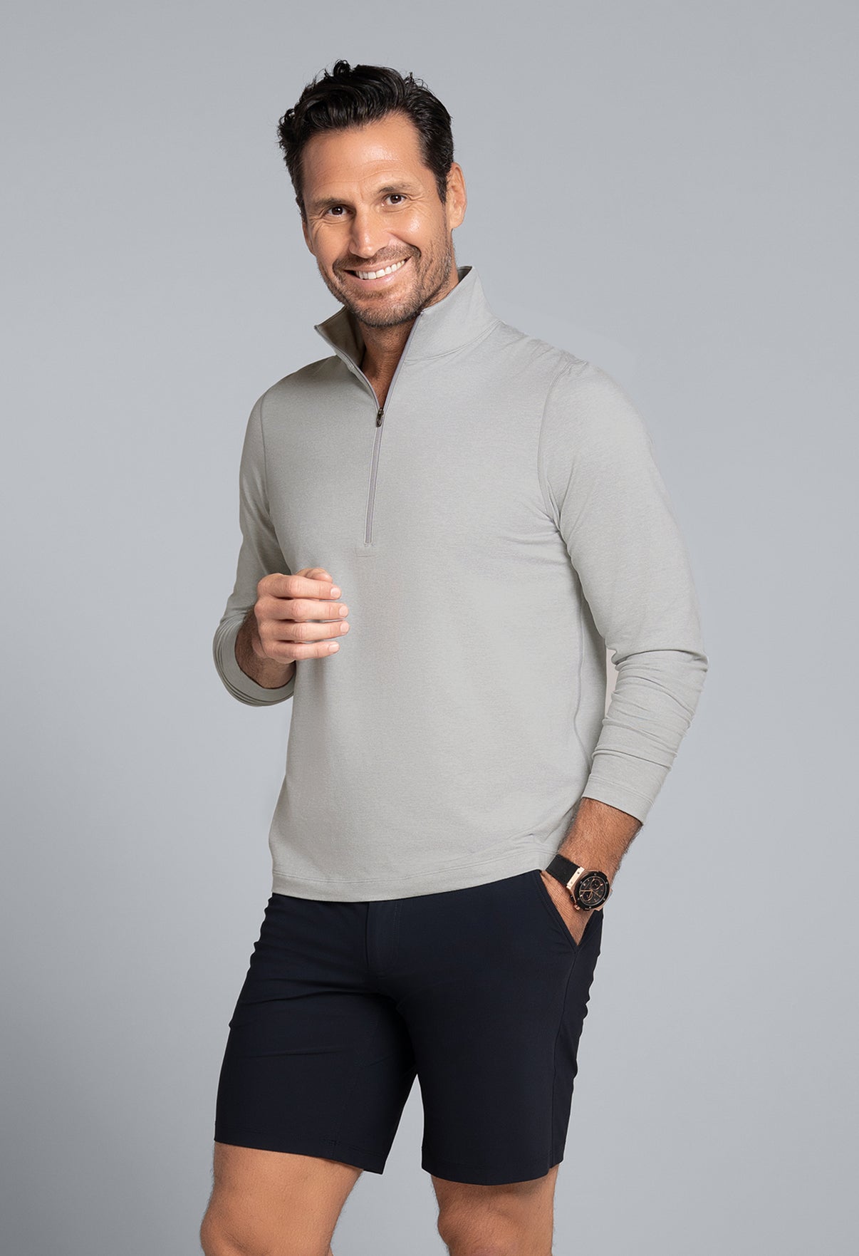 Man wearing a gray sweater and black shorts on a gray background