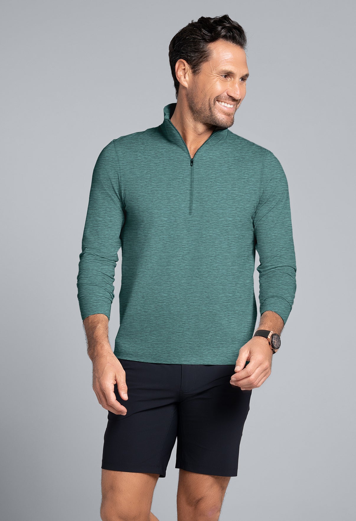 Man wearing a green long-sleeve shirt and black shorts on a gray background