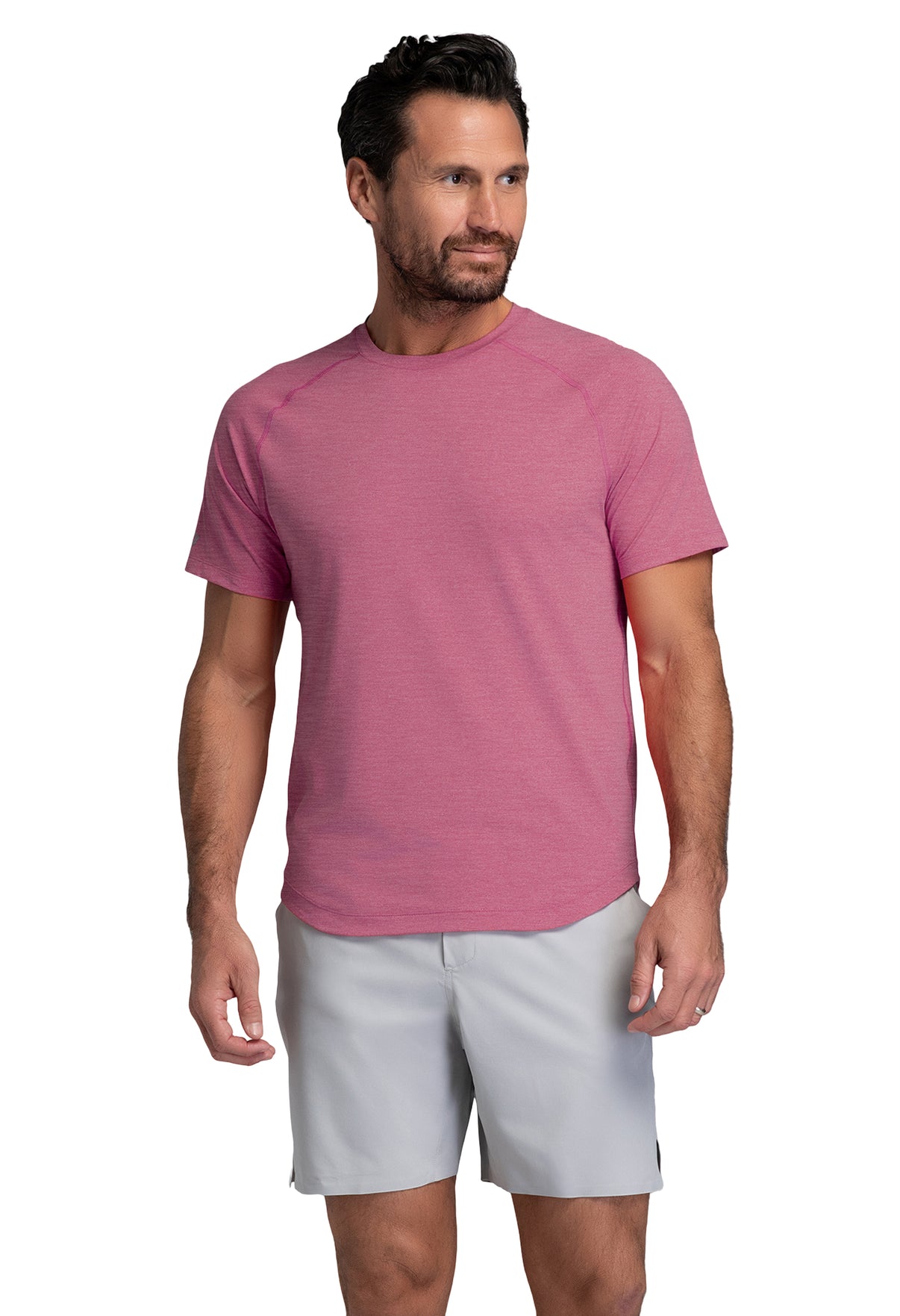 Man wearing a pink t-shirt and light gray shorts on a white background