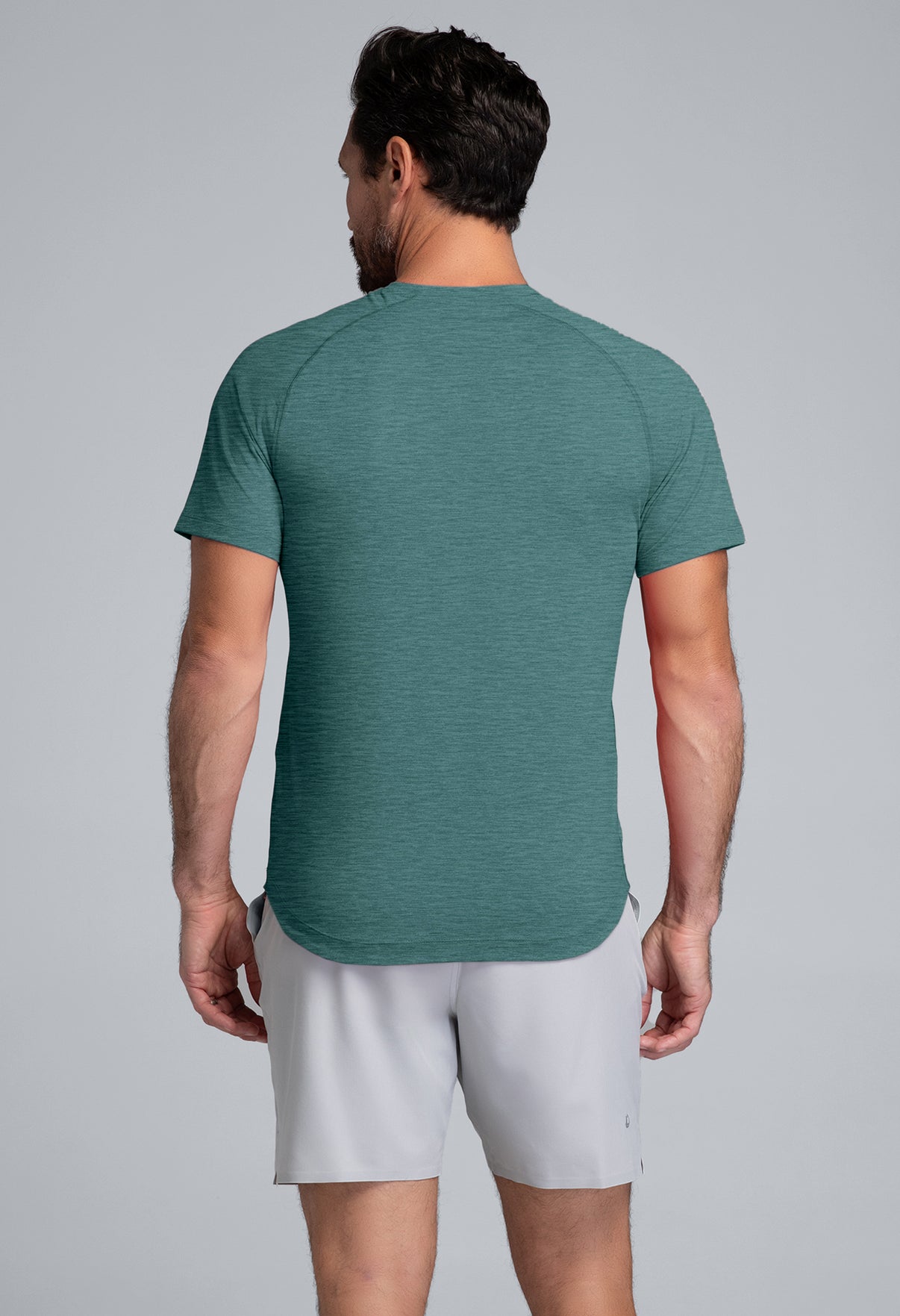 Man wearing a green athletic shirt and white shorts on a gray background