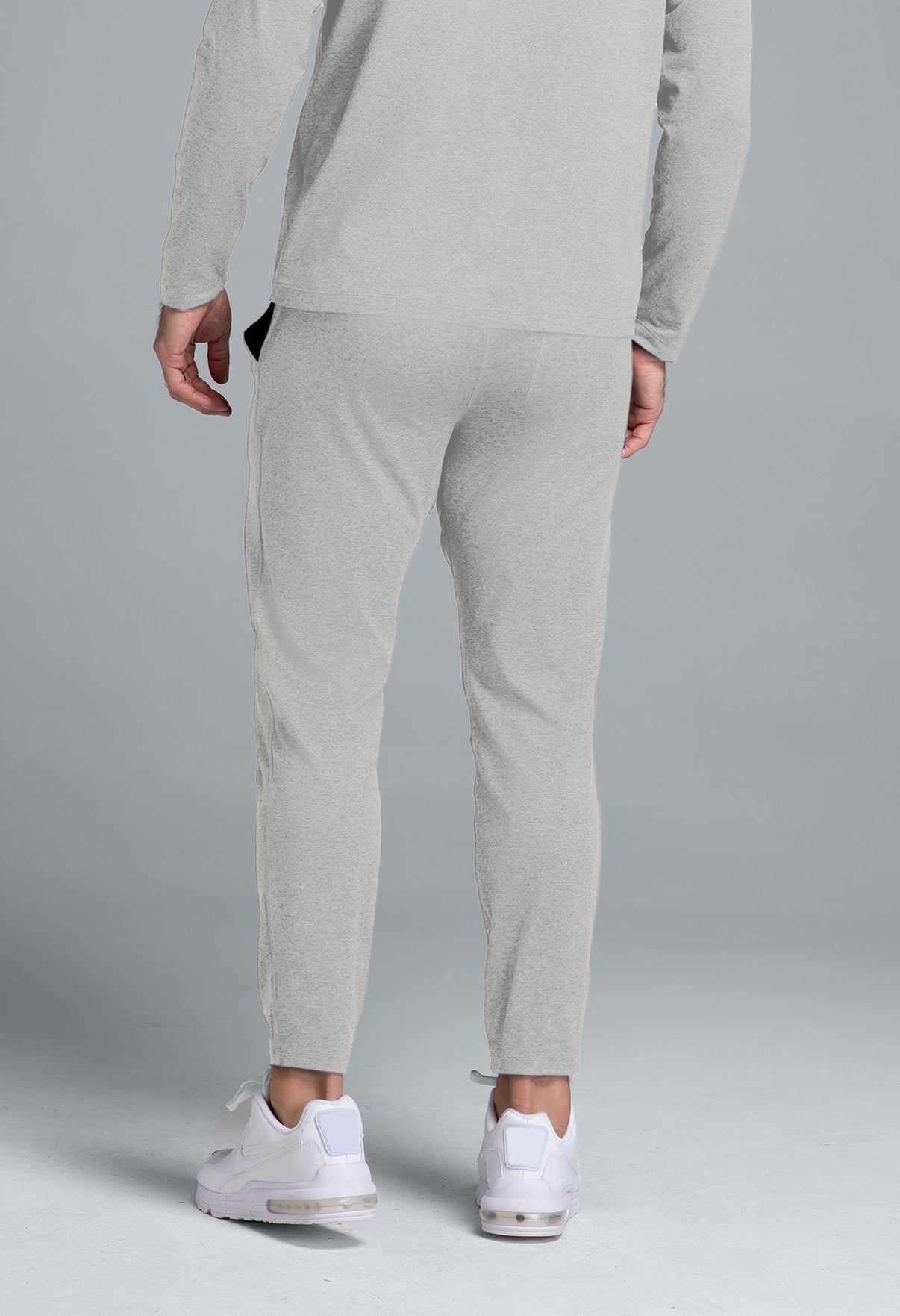 Person wearing a gray tracksuit with white sneakers on a gray background