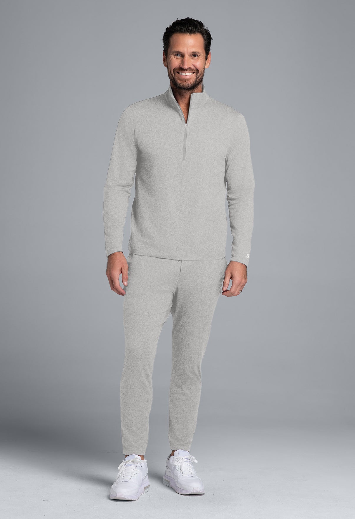 Man wearing a light gray outfit with a matching jacket and pants on a gray background