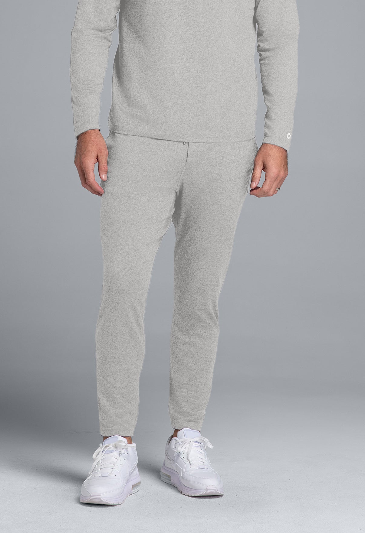 Person wearing a gray tracksuit with white sneakers on a gray background