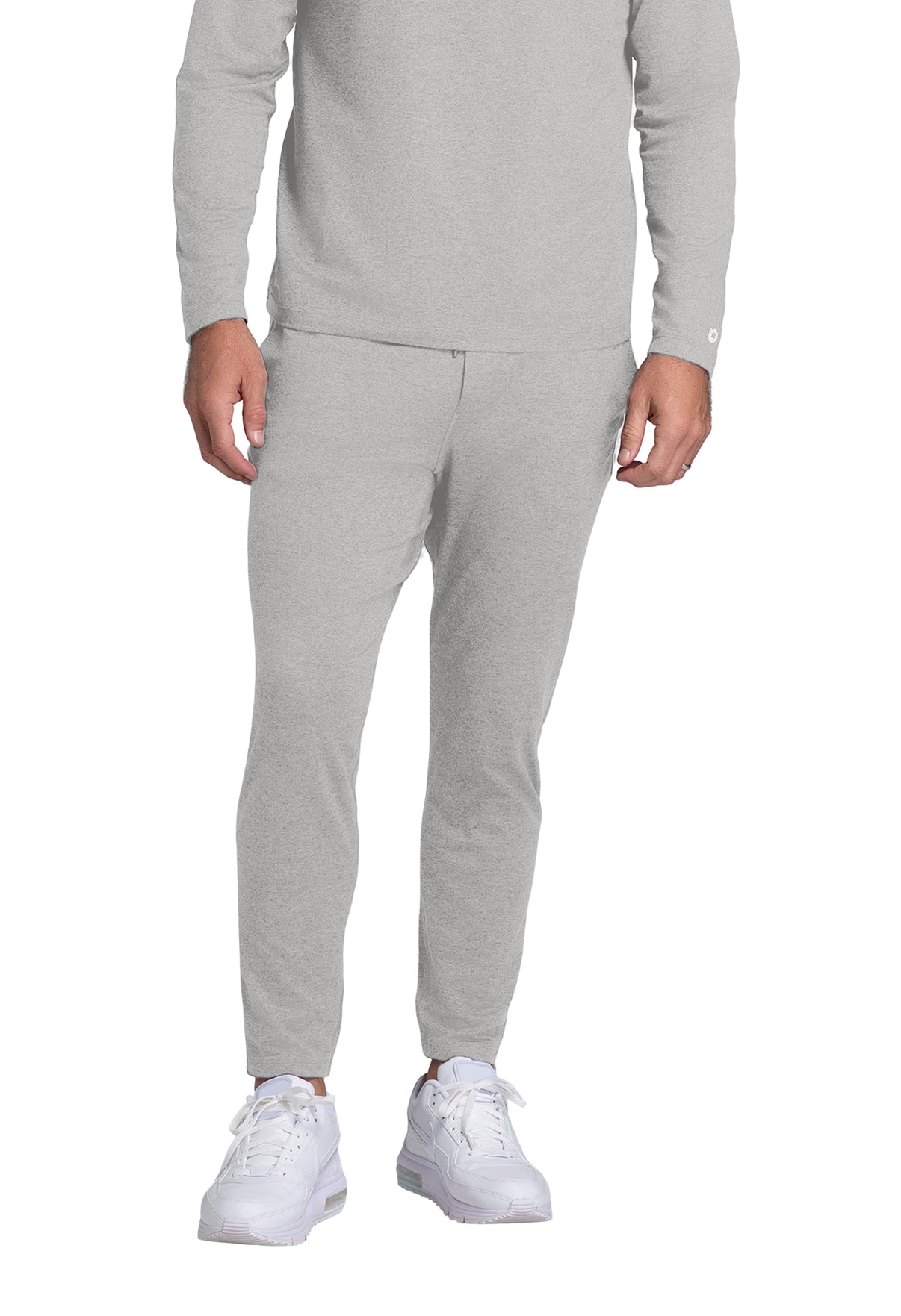 Person wearing a gray tracksuit with white sneakers on a white background