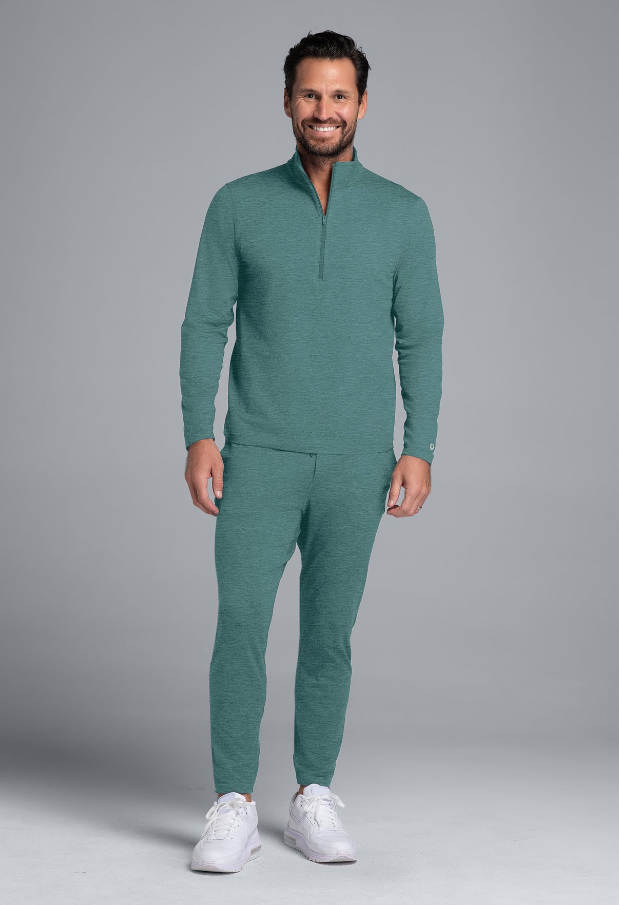 Man wearing a teal tracksuit on a gray background