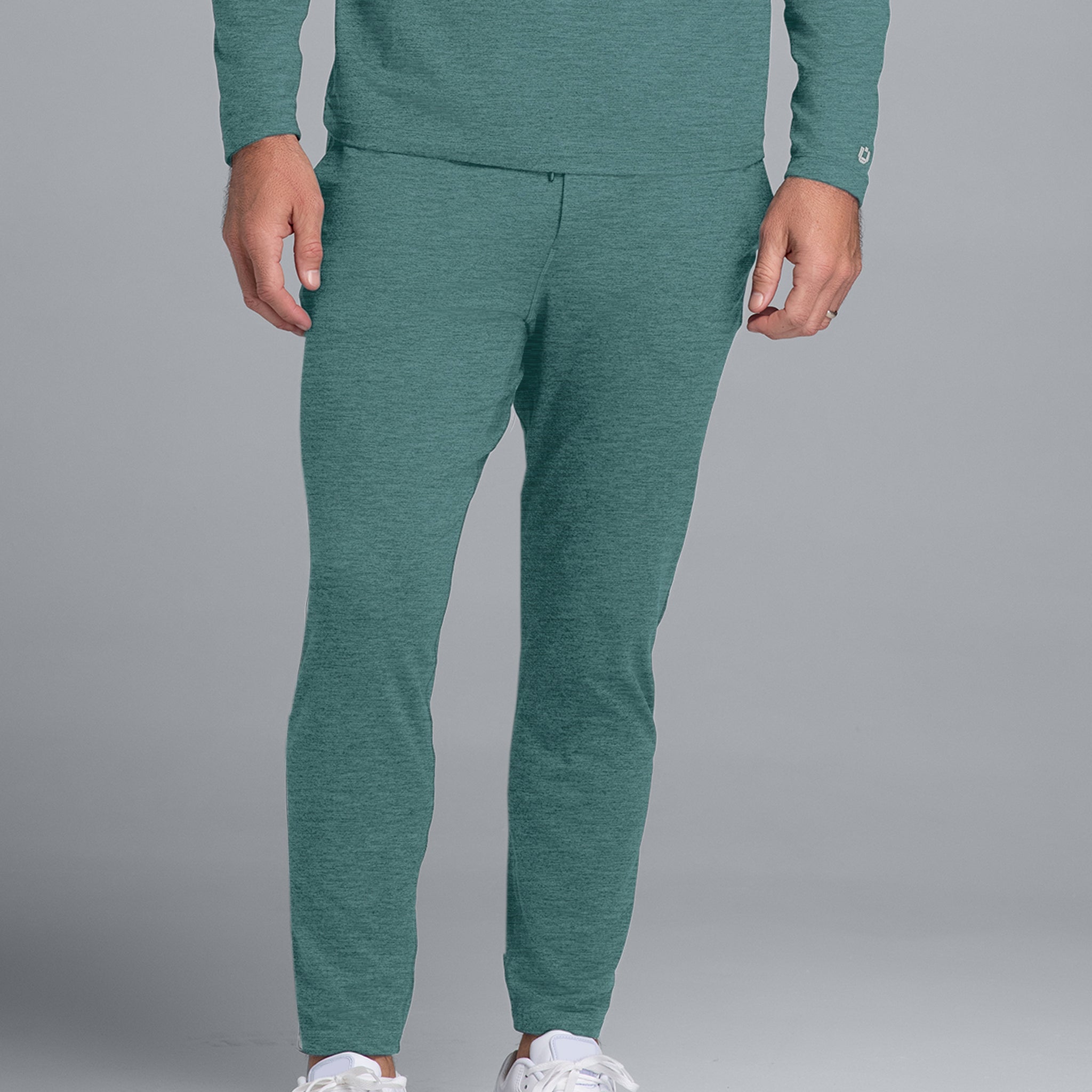 Person wearing a teal tracksuit with white sneakers on a gray background