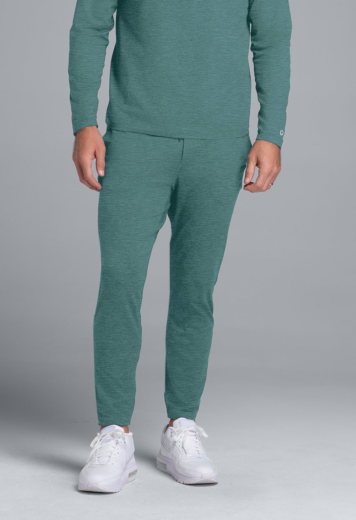 Person wearing a teal tracksuit with white sneakers on a gray background