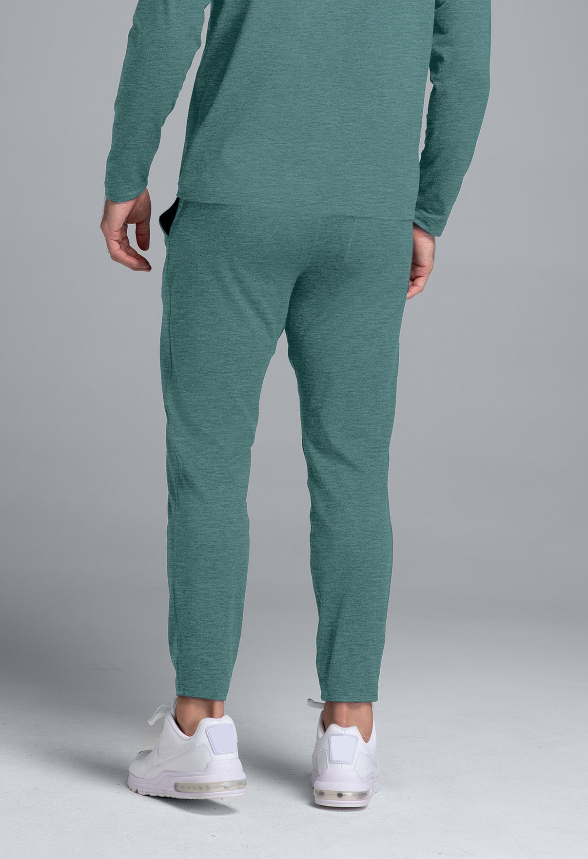 Person wearing a teal tracksuit with white sneakers on a gray background